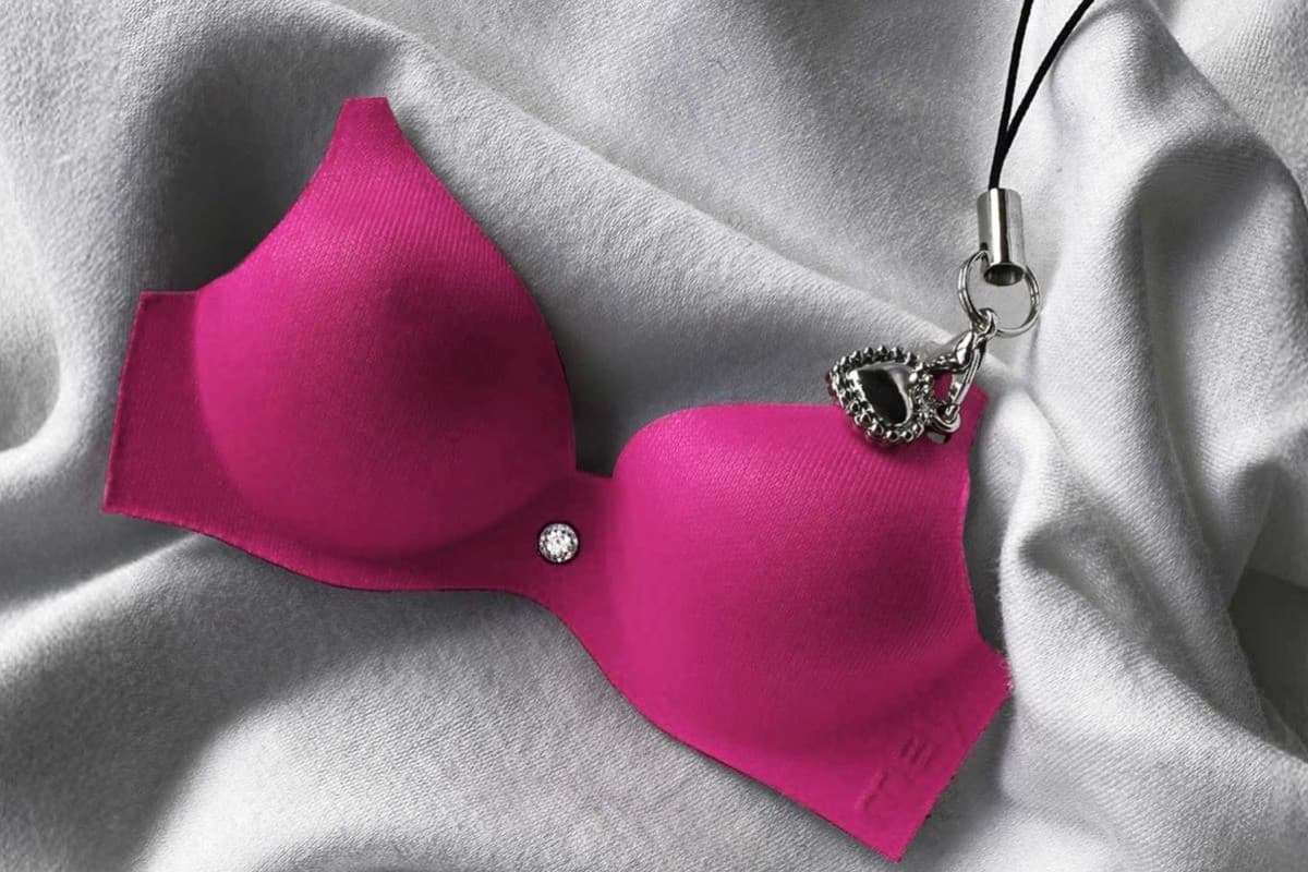 Pinker Mini-BH-Schlüsselanhänger, der auf einem weißen Stoff liegt.