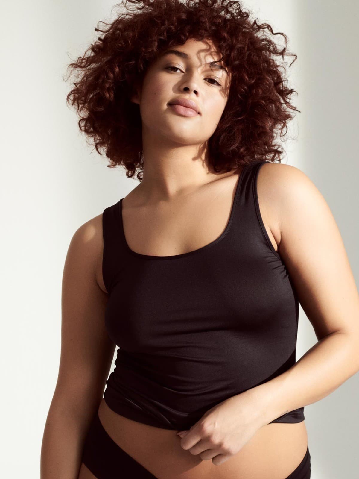 Weibliches Model trägt ein schwarzes Top mit passendem Slip in schwarz.