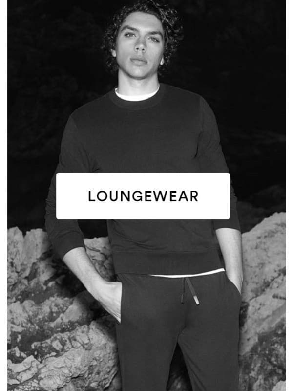 Schwarz/Weiß-Bild eines Männermodels, das ein dunkles Loungewear-Set aus Langarmshirt und langer Hose trägt.