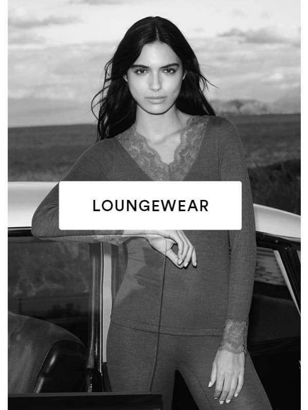 Zwart-witfoto van een model dat tegen een autodeur leunt en een set bestaat uit een shirt met lange mouwen en een legging uit de Wool Love-serie draagt.