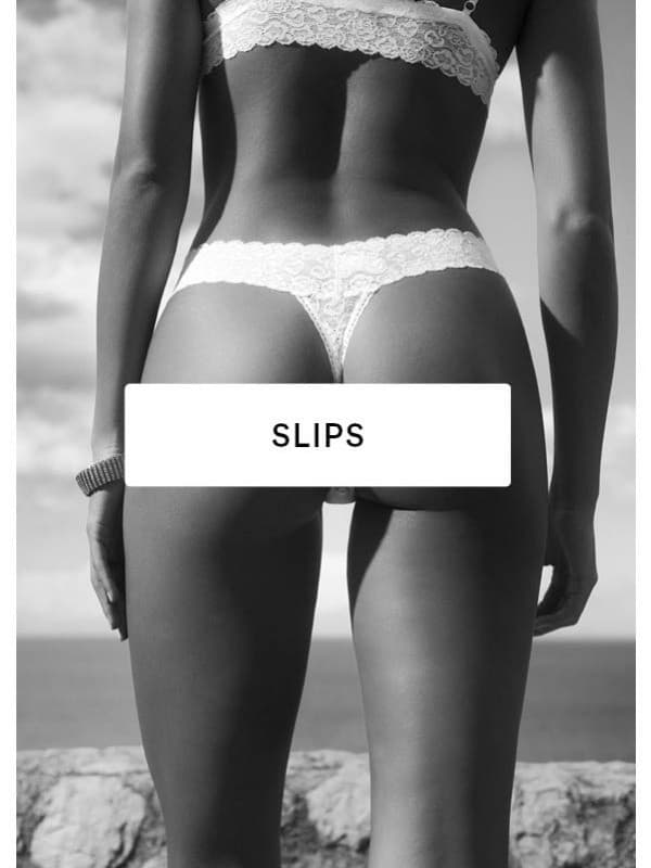 Zwart-witfoto van een vrouwelijk lichaam van achteren, gekleed in een kanten string.